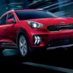 A red 2020 Kia Niro is driving at night with a blurred background.