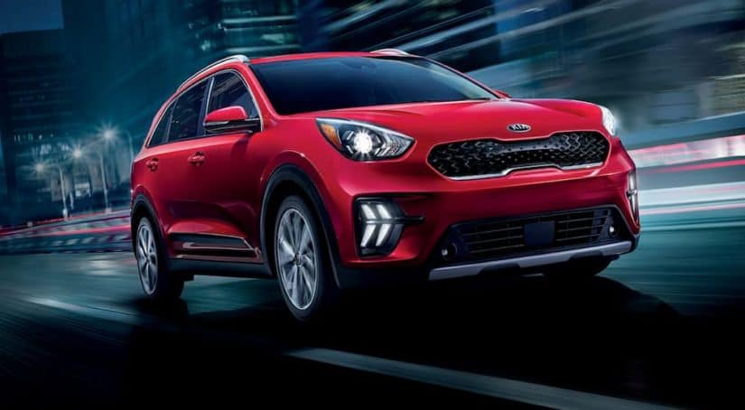A red 2020 Kia Niro is driving at night with a blurred background.