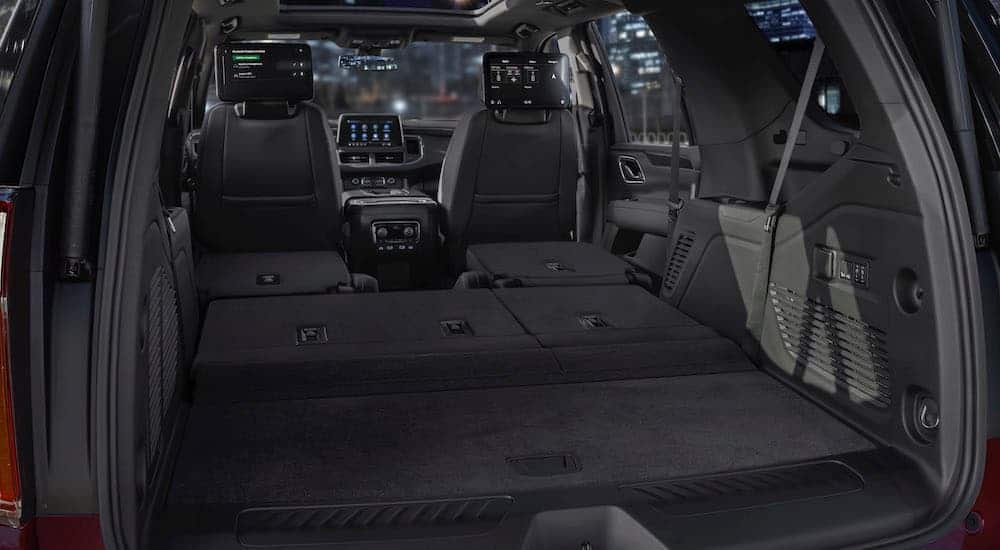 The black interior of a 2021 Chevy Tahoe is shown with the rear seats folded.