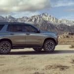 A grey 2021 Chevy Tahoe Z71 is parked off-road with snow covered mountains in the distance.