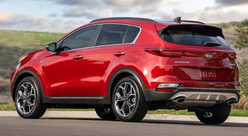 A red 2020 Kia Sportage is shown parked from the rear while waiting for a comparison on the 2021 Kia Sportage vs 2020 Kia Sportage.