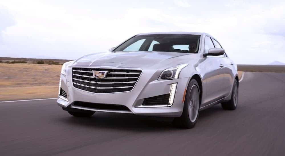 A silver 2018 Cadillac CTS, which is popular among Cadillac's used cars, is driving on an empty highway.