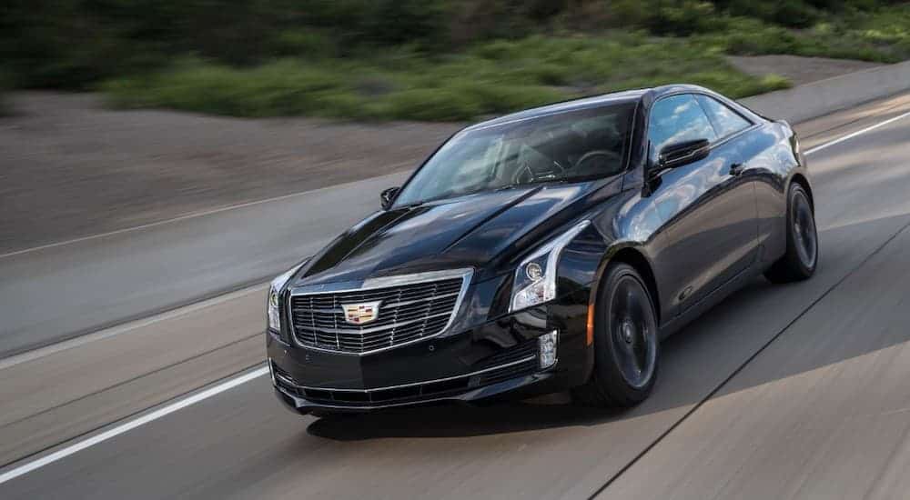 A black 2018 Cadillac ATS is taking a corner on a racetrack.