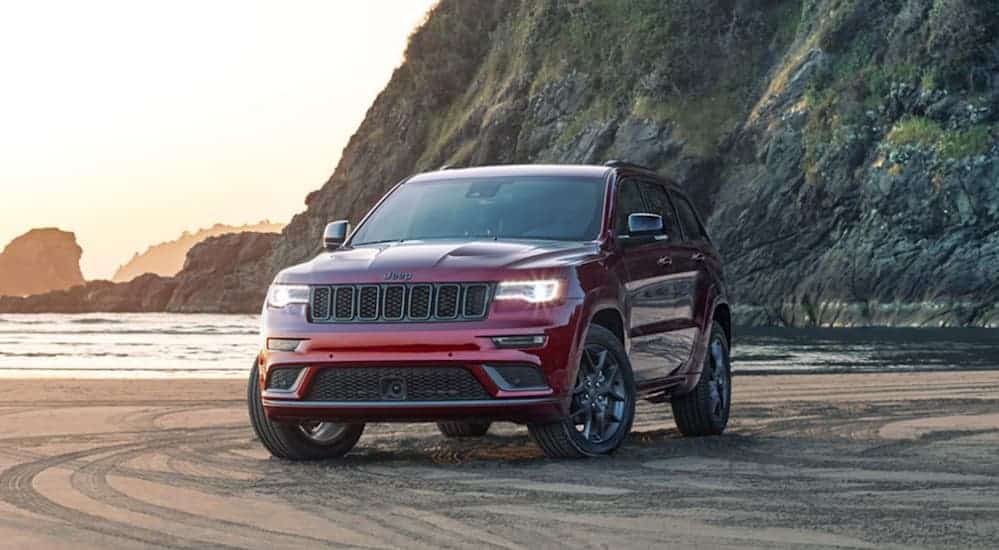 A red 2020 Jeep Grand Cherokee is parked on a beach.