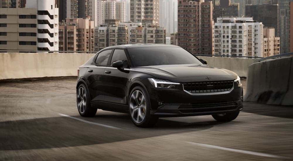 A black Polestar 2 is driving away from a city.