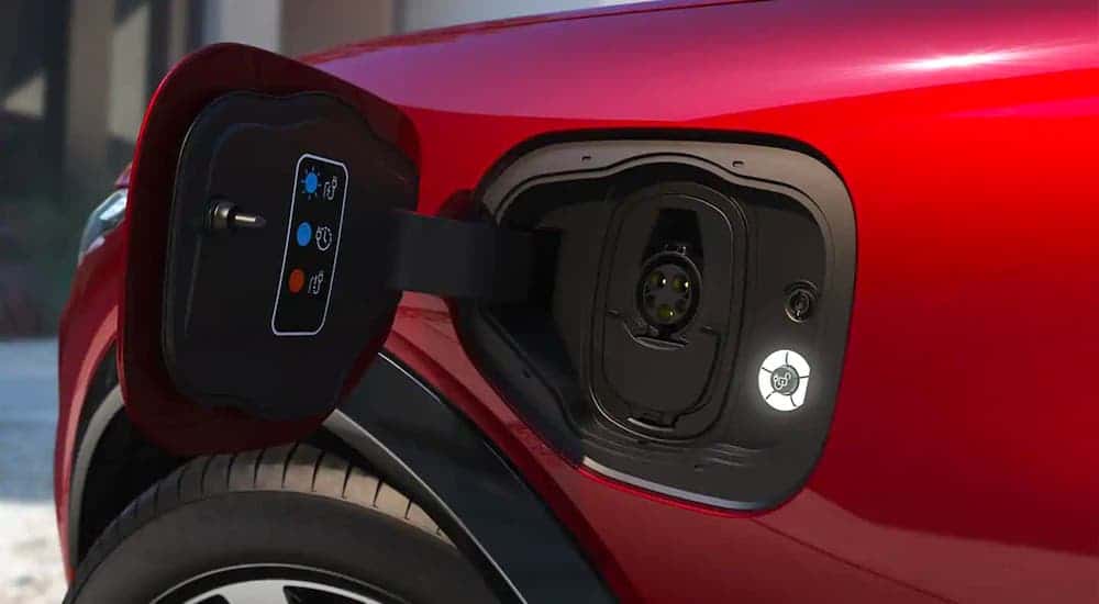 A closeup is shown of this Ford SUV's charging port on a red 2021 Ford Mustang Mach-E.