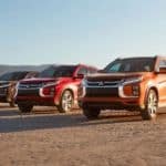 Three 2020 Mitsubishi Outlander Sports are in the desert with mountains in the distance.