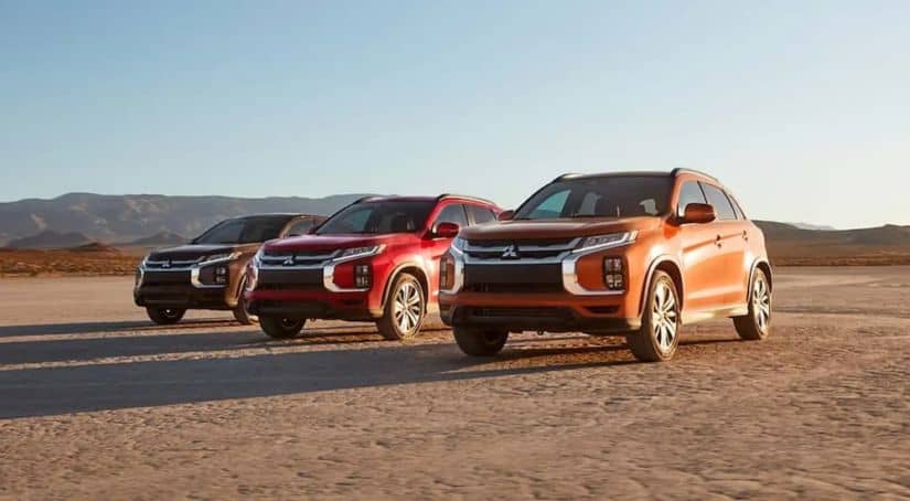Three 2020 Mitsubishi Outlander Sports are in the desert with mountains in the distance.