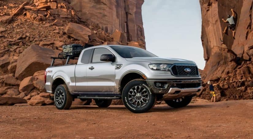 A silver 2020 Ford Ranger Is parked in the desert with rock climbers behind it.