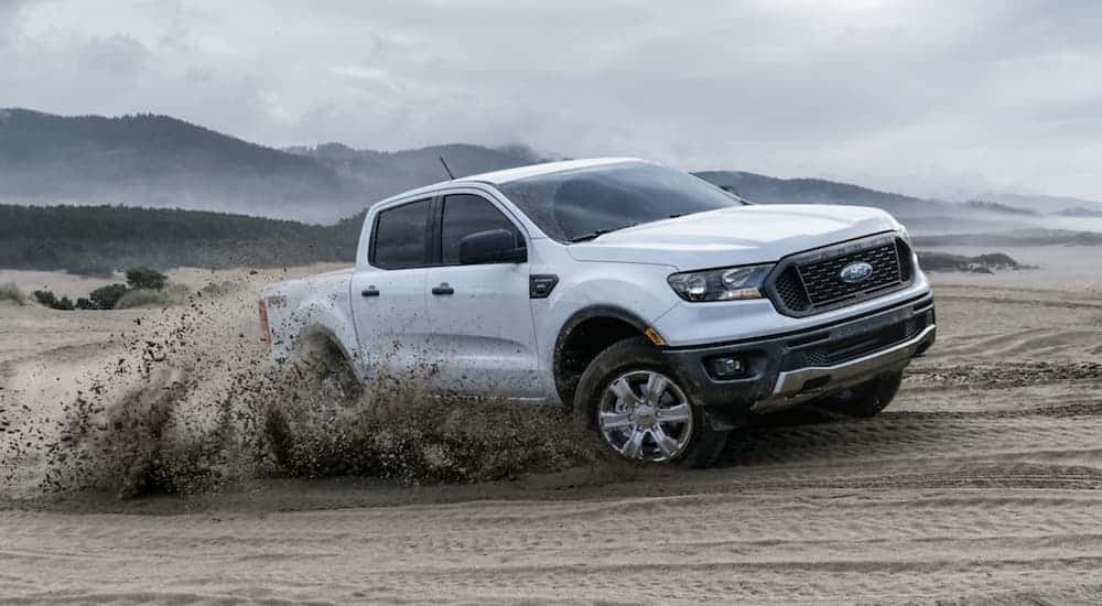 A white 2020 Ford Ranger is kicking up sand on a dune.