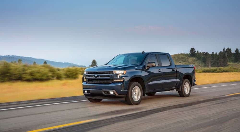 A blue 2020 Chevy Silverado RST is driving on a highway.