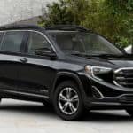A black 2020 GMC Terrain, wich wins when comapring the 2020 GMC Terrain vs 2020 Nissan Rogue, is parked in front of city steps and trees.
