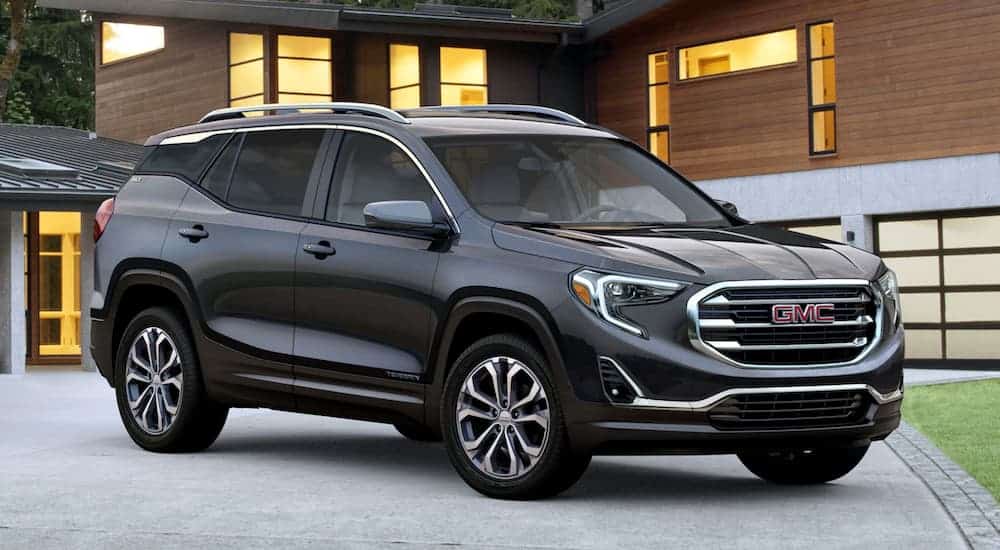A grey 2020 GMC Terrain is parked in front of a modern house.