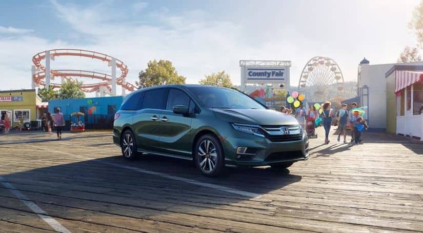 A green 2020 Honda Odyssey Elite is parked in front of a county fair.