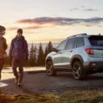 A couple is walking away from a silver 2020 Honda Passport for a sunrise hike.