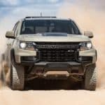 A tan 2021 Chevy Colorado ZR2 is shown from the front while racing through sand.