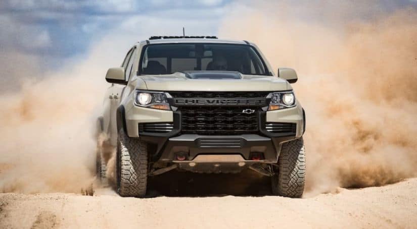 A tan 2021 Chevy Colorado ZR2 is shown from the front while racing through sand.