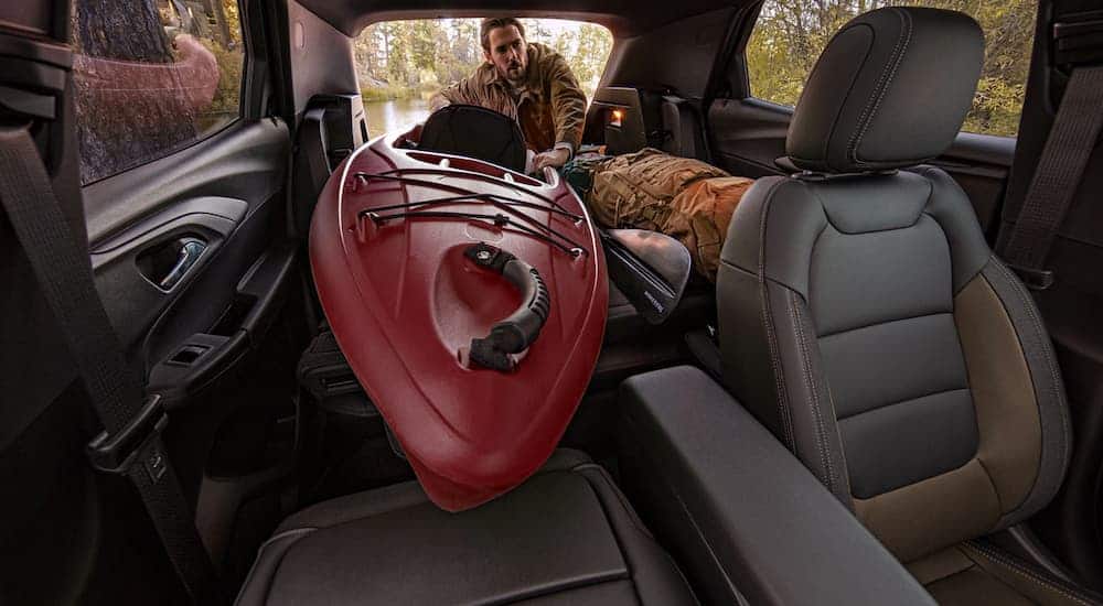 A man is loading a kayak into the cargo area of a 2021 Chevy Trailblazer.