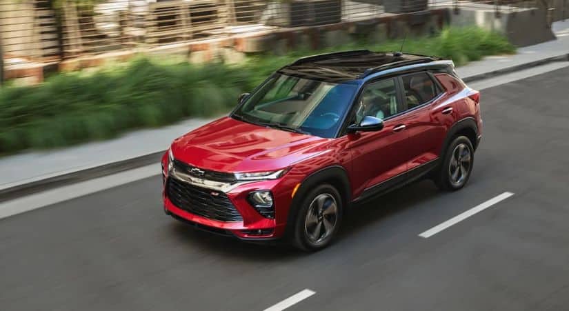 A red 2021 Chevy Trailblazer RS is driving past bushes after winning the 2021 Chevy Trailblazer vs 2020 Nissan Kicks comparison.