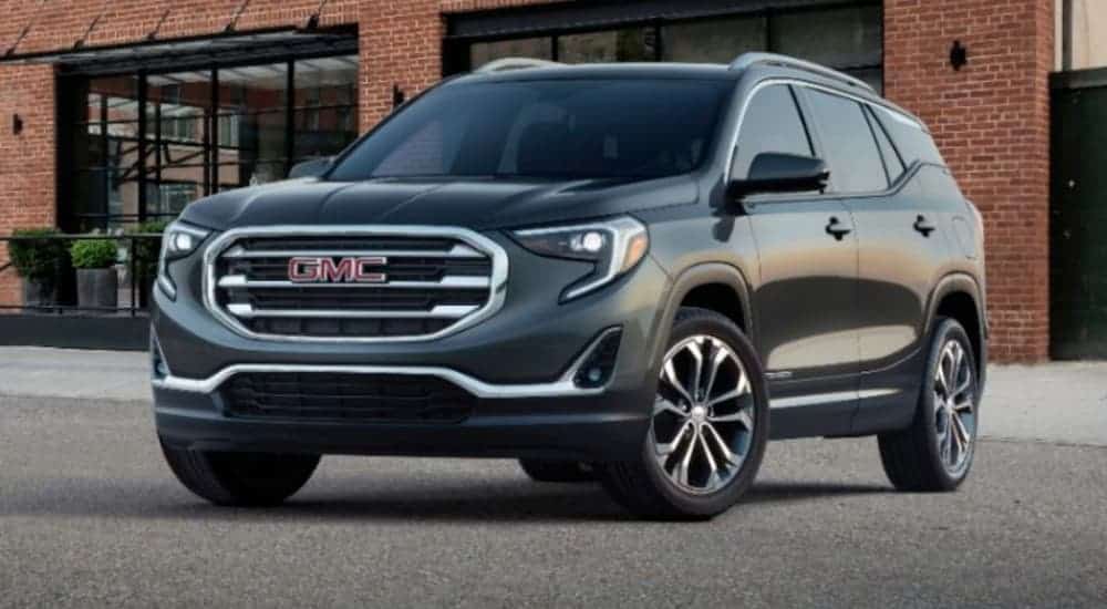 A grey 2020 GMC Terrain is parked outside a brick building.
