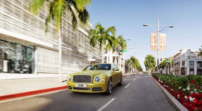 A yellow Bentley Mulsanne is driving down a city street.