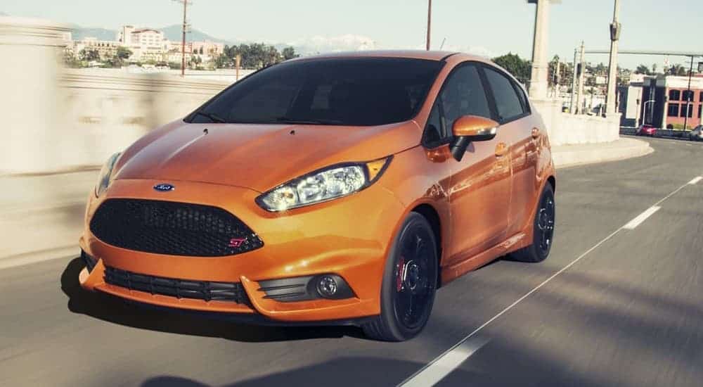 An orange 2019 Ford Fiesta ST is driving on a highway.