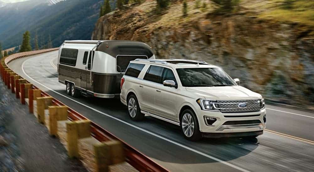 A white 2020 Ford Expedition is towing an Airstream on a mountain road.