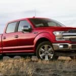 A red 2020 Ford F-150 is parked in a field after leaving a Ford dealer.