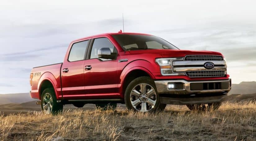 A red 2020 Ford F-150 is parked in a field after leaving a Ford dealer.