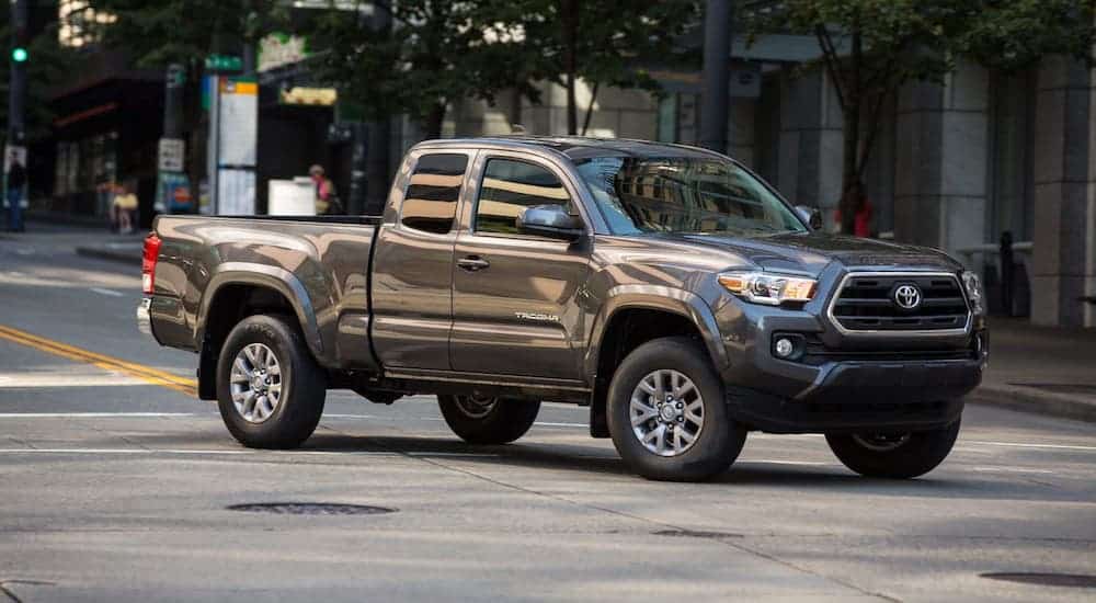A gray 2016 Toyota Tacoma is driving in a city.