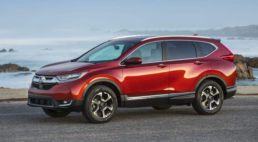 A red 2017 Honda CR-V is parked in front of a beach.
