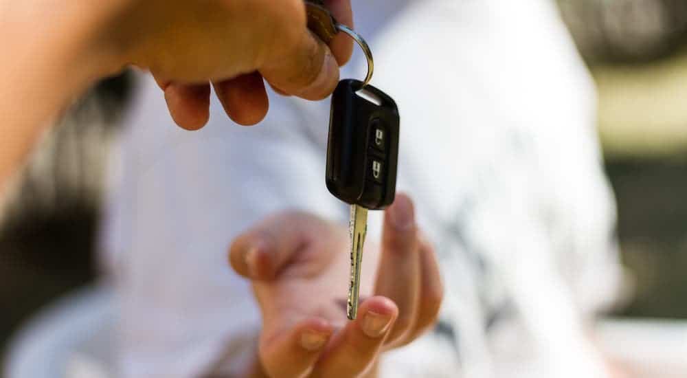 A car key is being handed from one person to another.