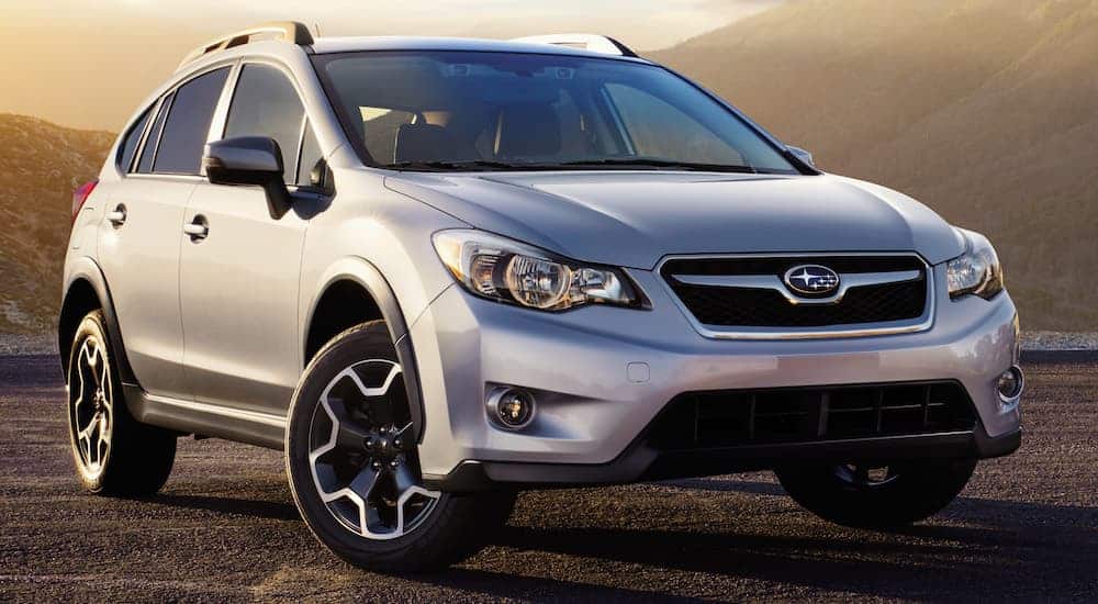 A silver 2015 Subaru Crosstrek is parked in front of a mountain at dusk.