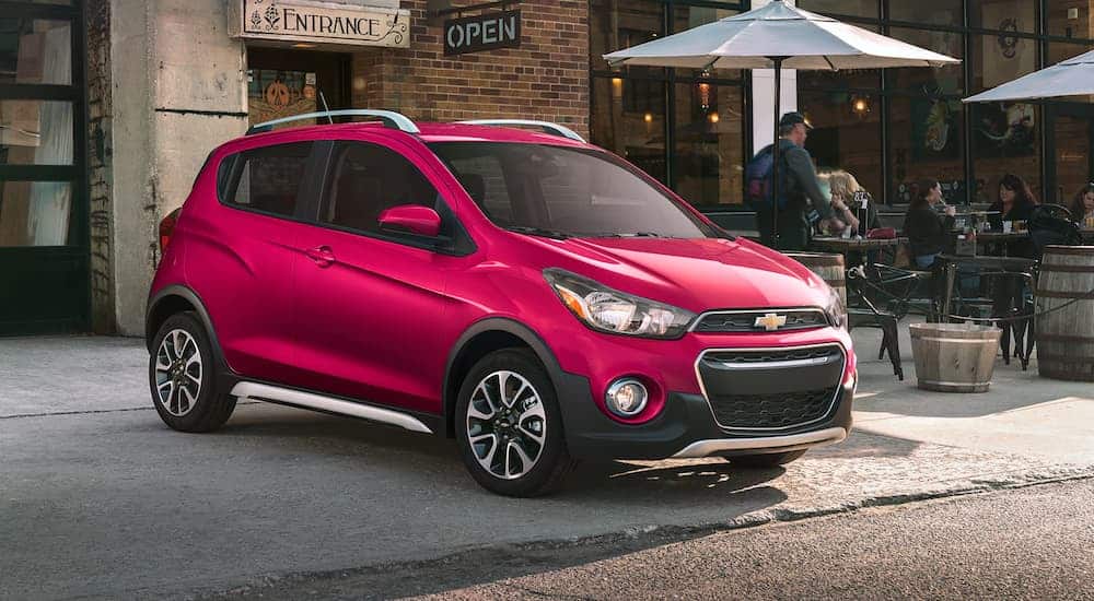 A dark pink 2020 Chevy Spark Activ is parked in front of a cafe.