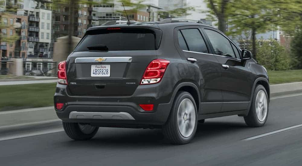 A dark grey 2020 Chevy Trax is driving down a city after winning the 2020 Chevy Trax vs 2020 Honda HR-V comparison.