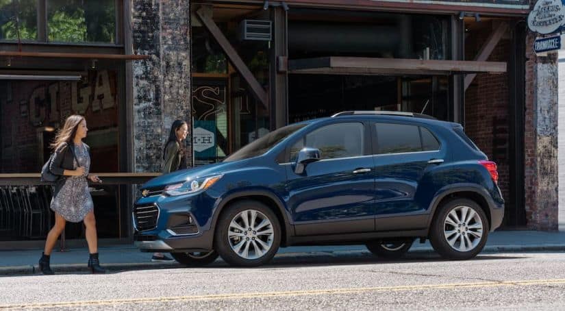 Two women are walking toward a blue 2020 CHevy Trax, parked on a city street after winning the 2020 Chevy Trax vs 2020 Nissan Kicks comparison.