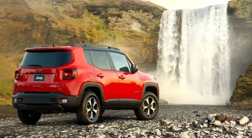 A red 2020 Jeep Renegade is facing away towards a waterfall.