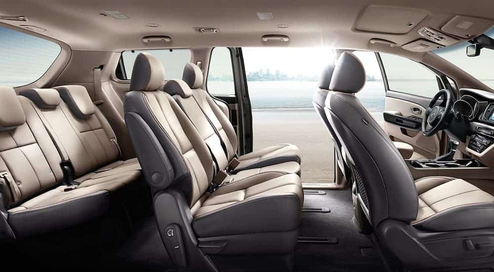 The tan interior of a 2020 Kia Sedona is shown with the back seat door open.