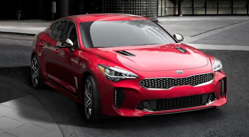 A red 2020 Kia Stinger is driving on a city street.