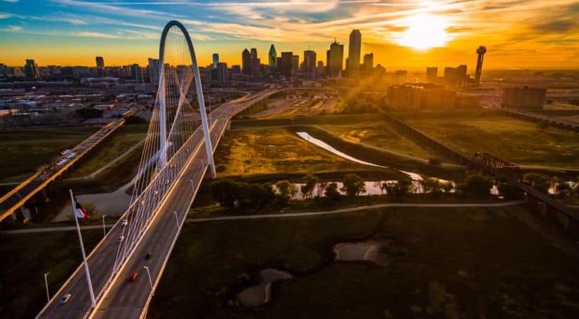 A drone view of Dallas, TX, during sunset is shown.