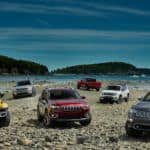The 2020 Jeep lineup that can be found at a Jeep dealer near me, is parked on a rocky beach shore with islands.