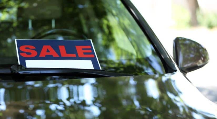 A sale sign is in the window of a car before the owner was told to 'sell us your car' by a dealership.