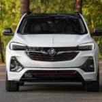 A white 2020 Buick Encore GX that is parked on a woodland road is shown from the front.
