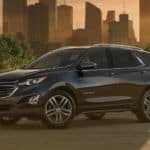 A black 2020 Chevy Equinox is in front of a city skyline at sunset after winning the 2020 Chevy Equinox vs 2020 Ford Escape comparison.