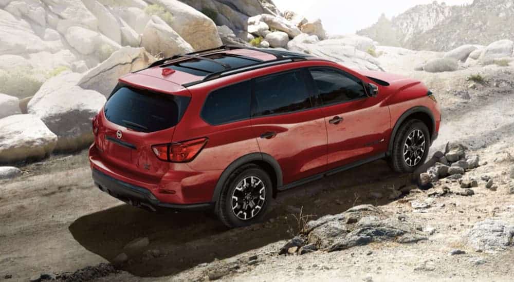 A red 2020 Nissan Pathfinder is off-roading on a dirt trail.