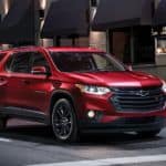 A red 2020 Chevy Traverse is stopped at a city intersection at night after winning the 2020 Chevy Traverse vs 2020 Nissan Pathfinder comparison.