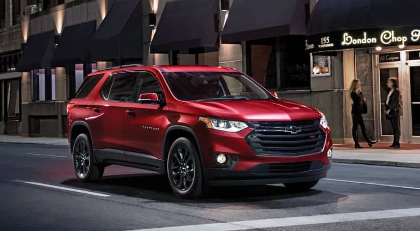 A red 2020 Chevy Traverse is stopped at a city intersection at night after winning the 2020 Chevy Traverse vs 2020 Nissan Pathfinder comparison.