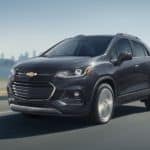 A black 2020 Chevy Trax is driving away from a city after winning the 2020 Chevy Trax vs 2020 Buick Encore comparison.