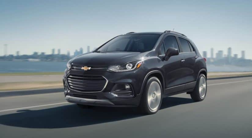 A black 2020 Chevy Trax is driving away from a city after winning the 2020 Chevy Trax vs 2020 Buick Encore comparison.