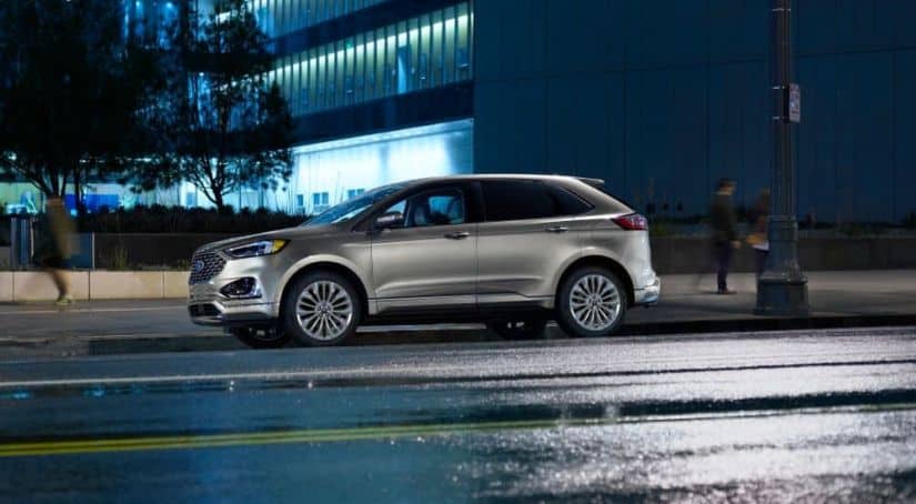 A silver 2020 Ford Edge is parked on a city street at night.